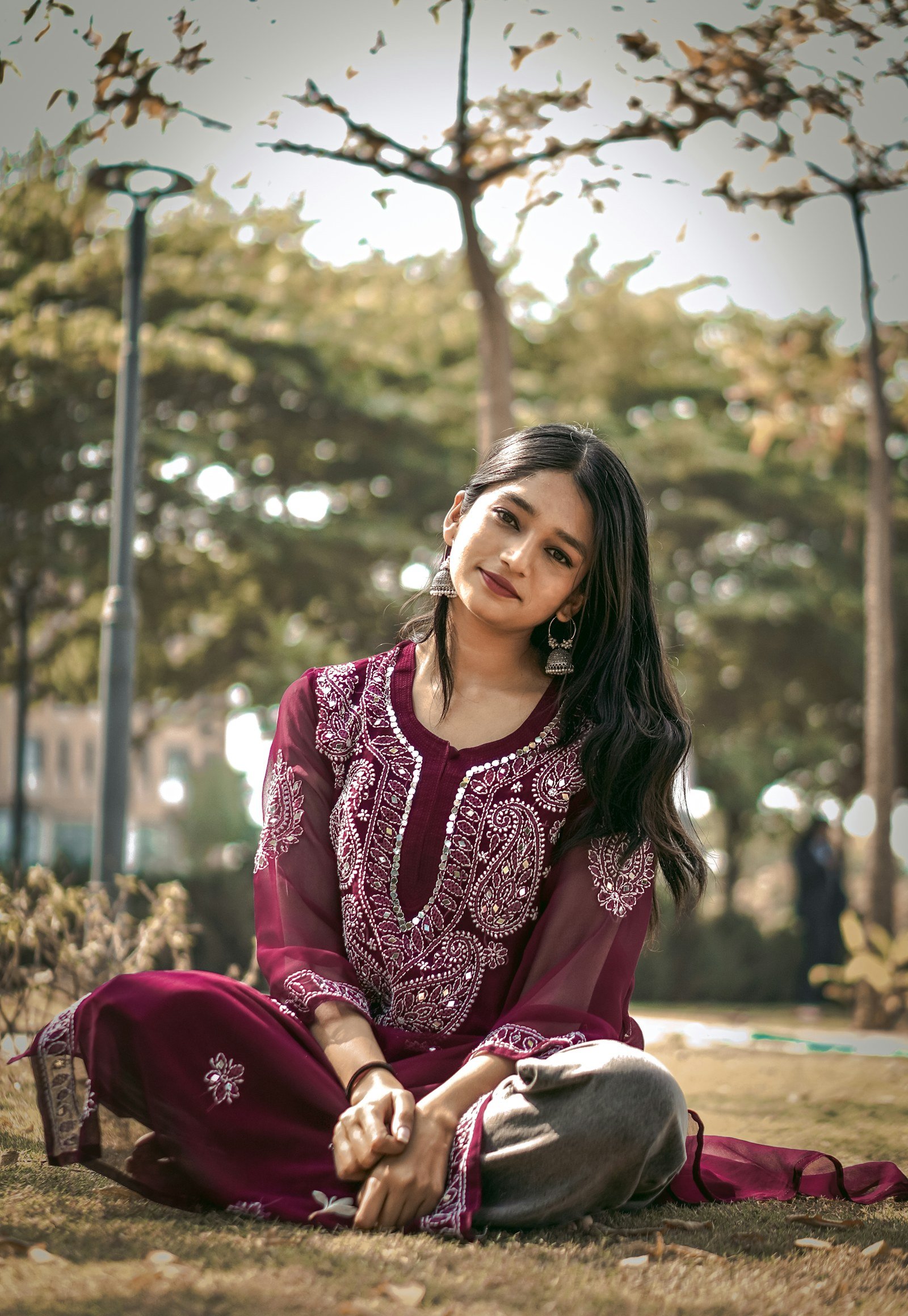 Woman in a maroon embroidered kurta sitting in a park